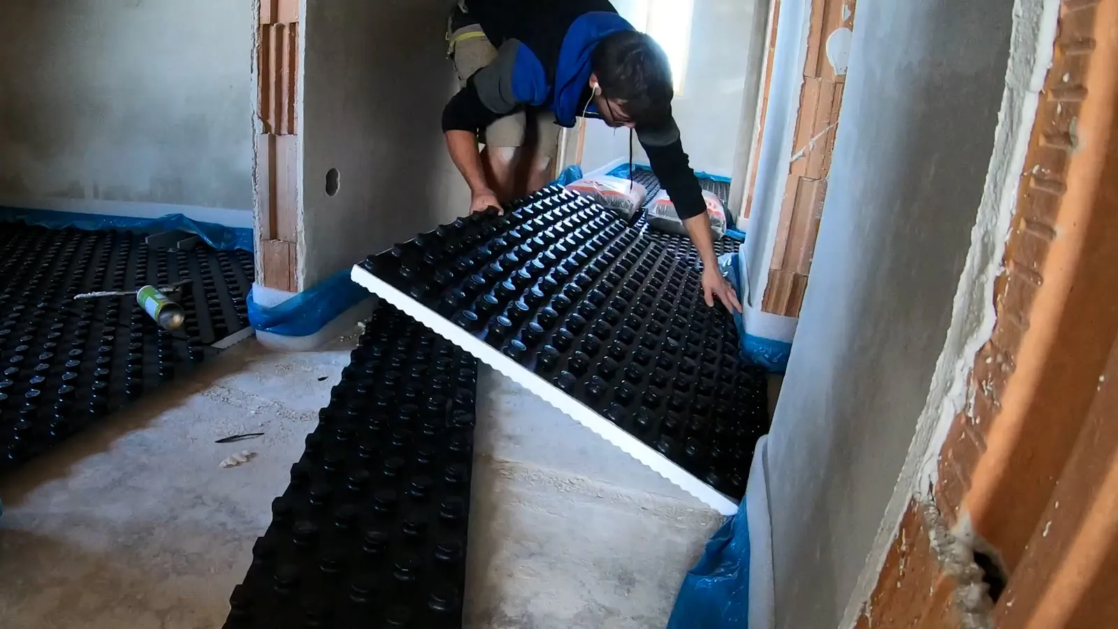 Pokládání nopové fólie pro podlahové topení u stěny